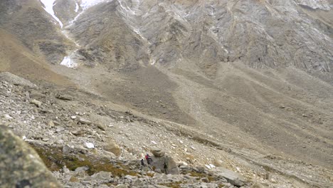 3-hikers-are-resting-by-a-large-boulder-in-the-a-glacial-moraine-in-Patagonia,-Chile