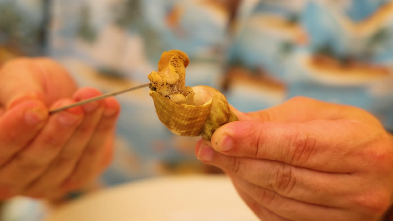 persona que extrae almejas de la concha con una herramienta