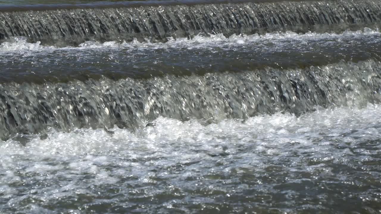 Splashing water flows over a small artificial cascade waterfall
