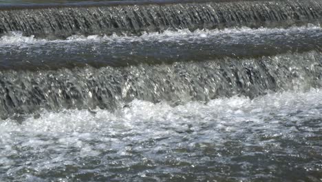 splashing water flows over a small artificial cascade waterfall