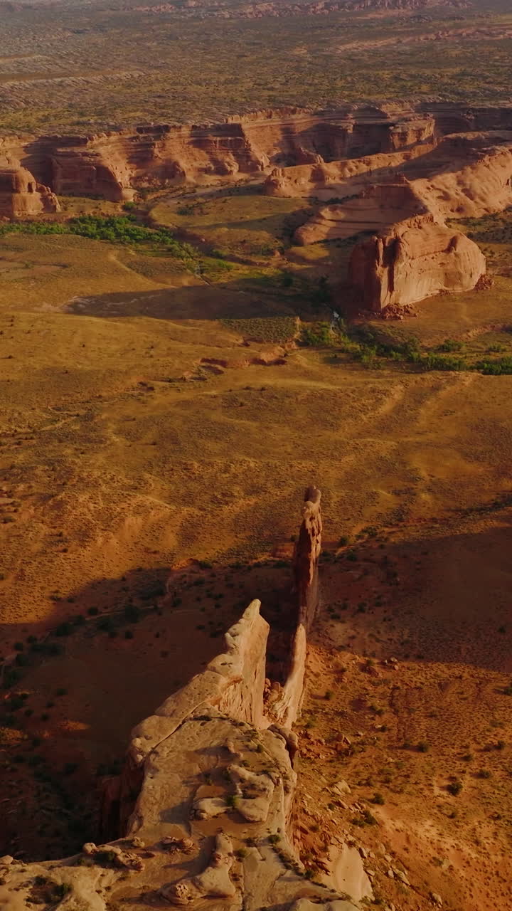 Deserted dry land with big stunning rocks of canyons. Sunlit panorama of Arches National Park from aerial perspective. Vertical video