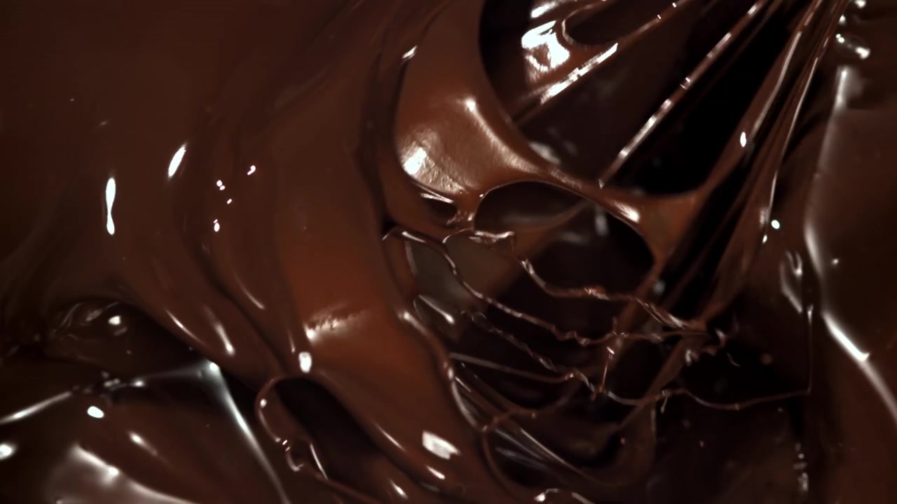 Frusta che mescola cioccolato fuso ricco e lucido al rallentatore