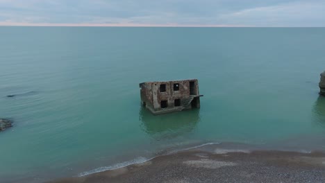 aerial view of abandoned seaside fortification buildings at karosta northern forts on the beach of baltic sea , overcast day, wide drone shot moving forward, tilt down