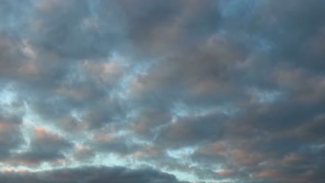 Ondeando-Patrones-De-Pequeñas-Nubes-Cúmulos-En-Diferentes-Direcciones-Con-Puesta-De-Sol-Colorida-Y-Tonos-Oscuros-De-Hora-Azul