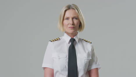 Studio-Portrait-Of-Serious-Mature-Female-Airline-Pilot-Or-Ship-Captain-Against-Plain-Background