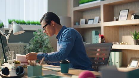 inspired man checking notebook flipping pages office. businessman working alone