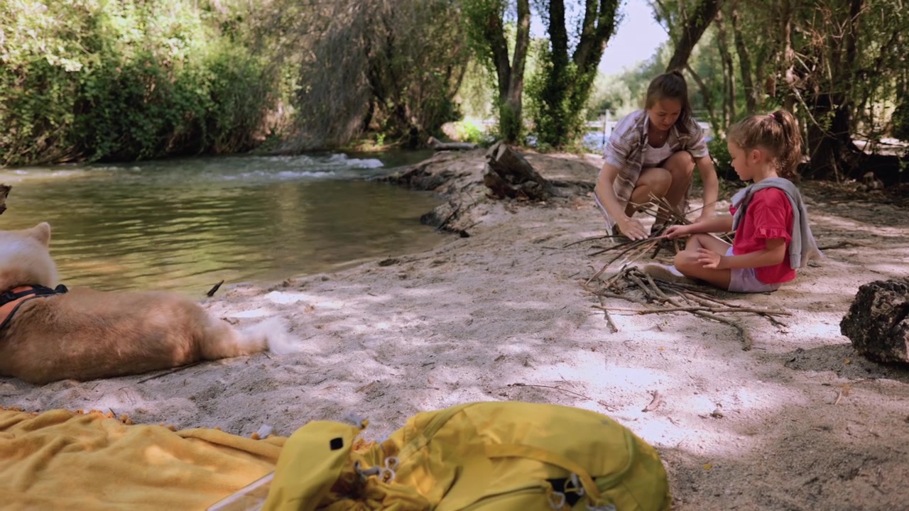 Madre e hija haciendo una fogata junto al río