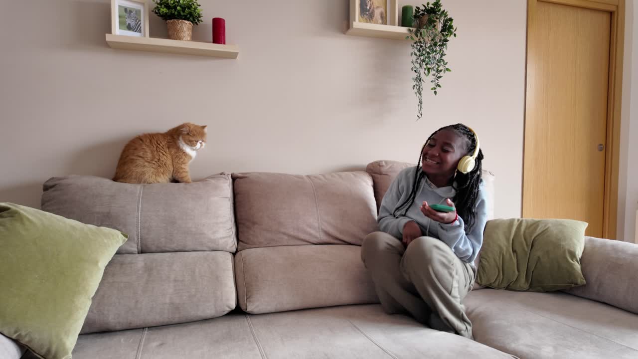 Woman listening to music with cat on couch