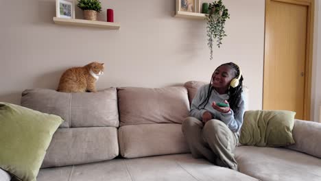 woman listening to music with cat on couch
