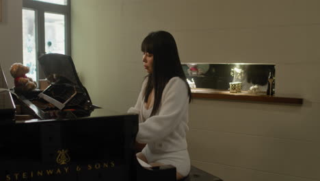 una chica asiática practicando el piano en casa.