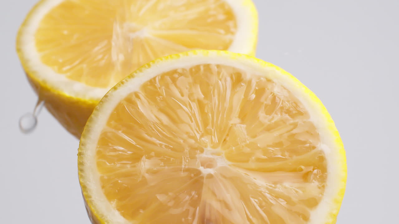 tiro macro de cámara lenta de agua que fluye de la rodaja de limón sobre fondo blanco