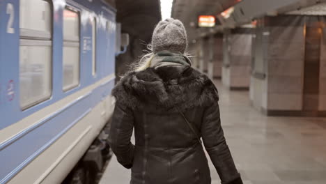 a person waits on a train platform next to a train