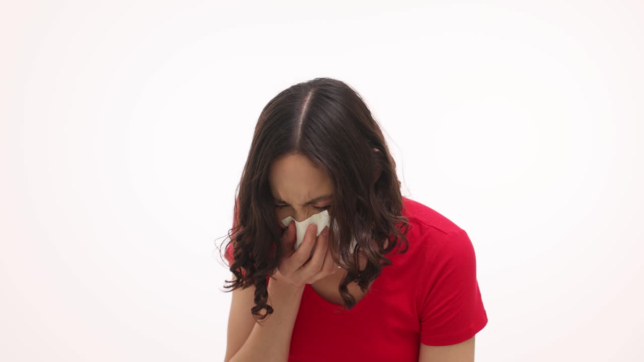 Woman sneezing or blowing her nose with a tissue due to allergies or a cold