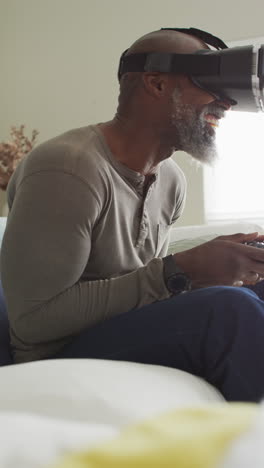 video vertical de un hombre afroamericano feliz en auriculares vr jugando videojuegos