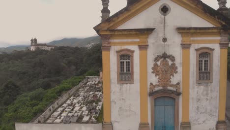 aerial descend showing the facade of our lady of mercy and charity church in ouro preto, minas gerais, brazil, with the saint fransisco de paulo church in the background on an overcast morning
