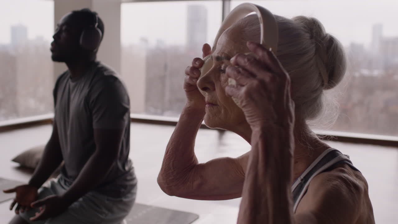 Elderly Woman and Man in Yoga Class with Headphones