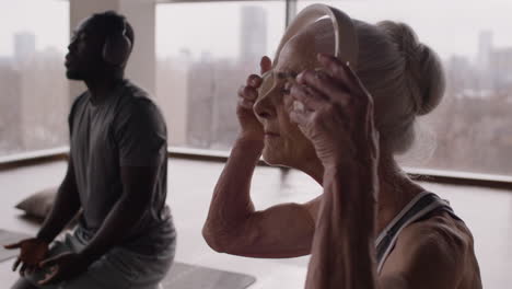 elderly woman and man in yoga class with headphones