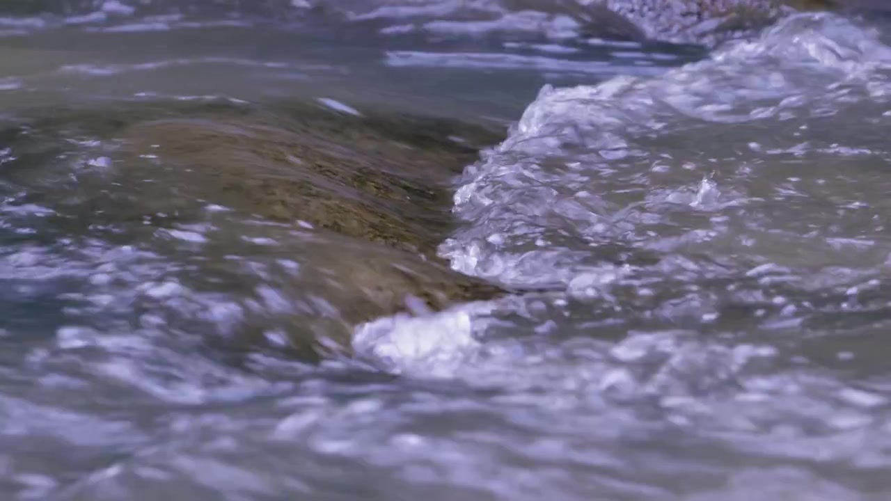 Superficie di un ruscello forestale poco profondo di acqua dolce, con piccole onde turbolente e increspature.