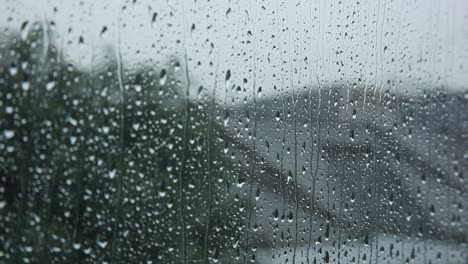 gotas de lluvia en la ventana de vidrio transparente cayendo en cascada, cierre la profundidad de enfoque estática y superficial