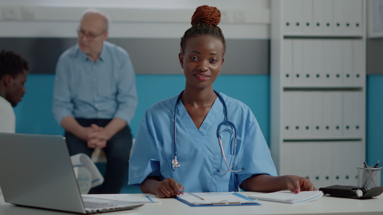 Young adult nurse sitting at desk with laptop