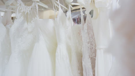 close up of beautiful bridal wedding dresses hanging on rail in shop