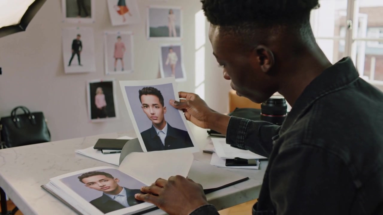 Pulling print, man in coat comparing portrait with portfolio at studio selecting shots, copy space