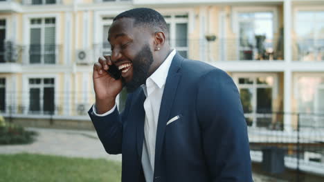 Emotional-african-businessman-calling-smartphone-outdoors.-Man-talking-phone