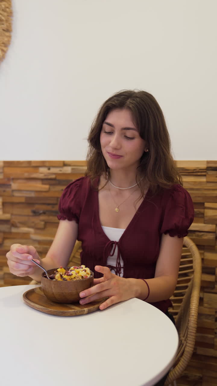 Young woman enjoying a delicious acai bowl in a trendy cafe, fully embracing a vibrant and healthy lifestyle filled with nutritious choices.