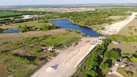 Flying-down-towards-construction-of-a-major-road-project-which-requires-a-bridge-to-cross-a-water-reservoir