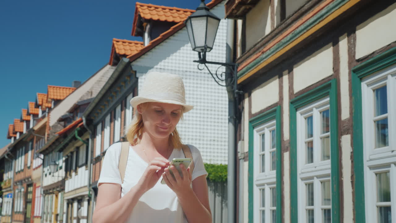 옛 독일 거리에서 스마트폰을 가진 여자