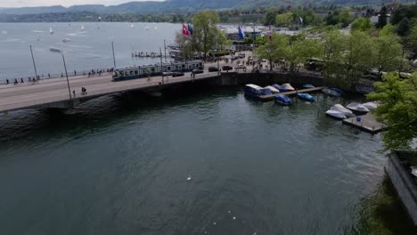 Forward moving drone shot showing bridge in the centre of Zurich with a tram crossing the bridge heading into the city