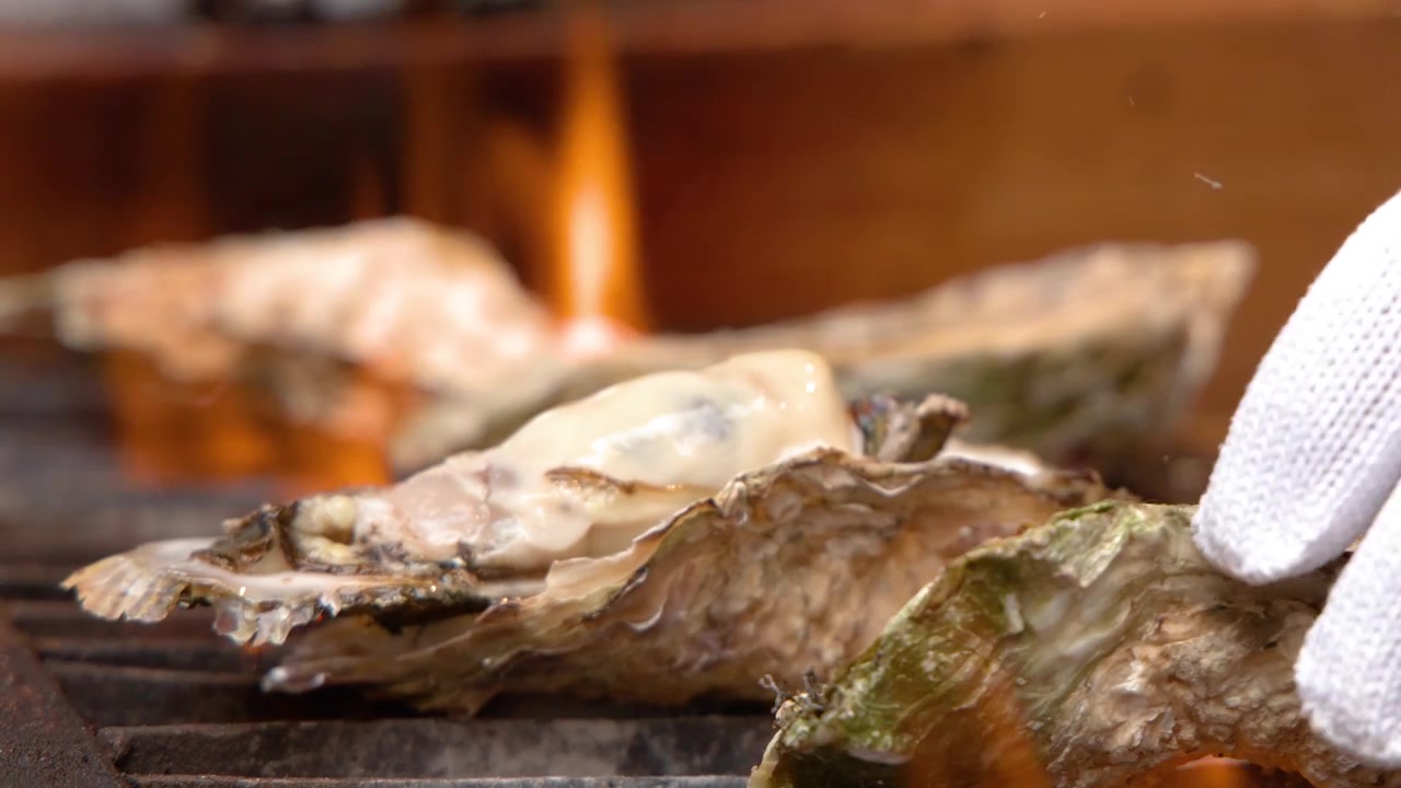 Chef Grilling Fresh Oysters Over Open Flame