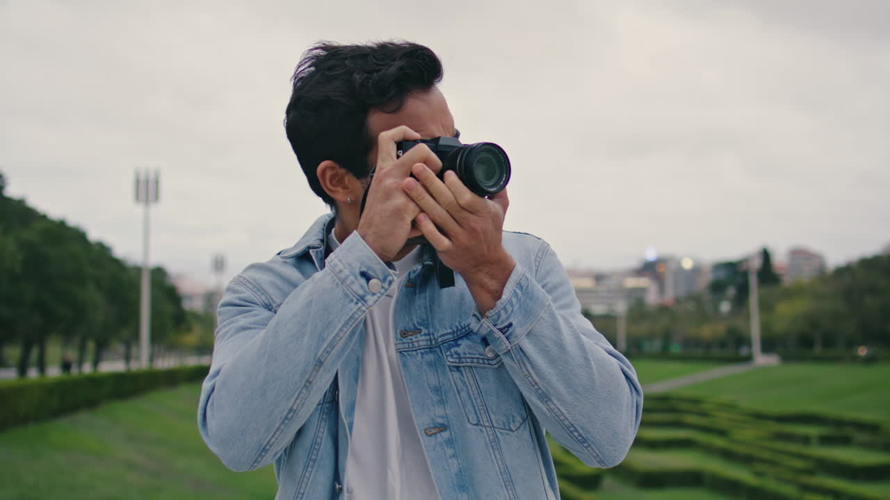 un tipo sin afeitar fotografiando la naturaleza del parque en una noche nublada de primavera de cerca.