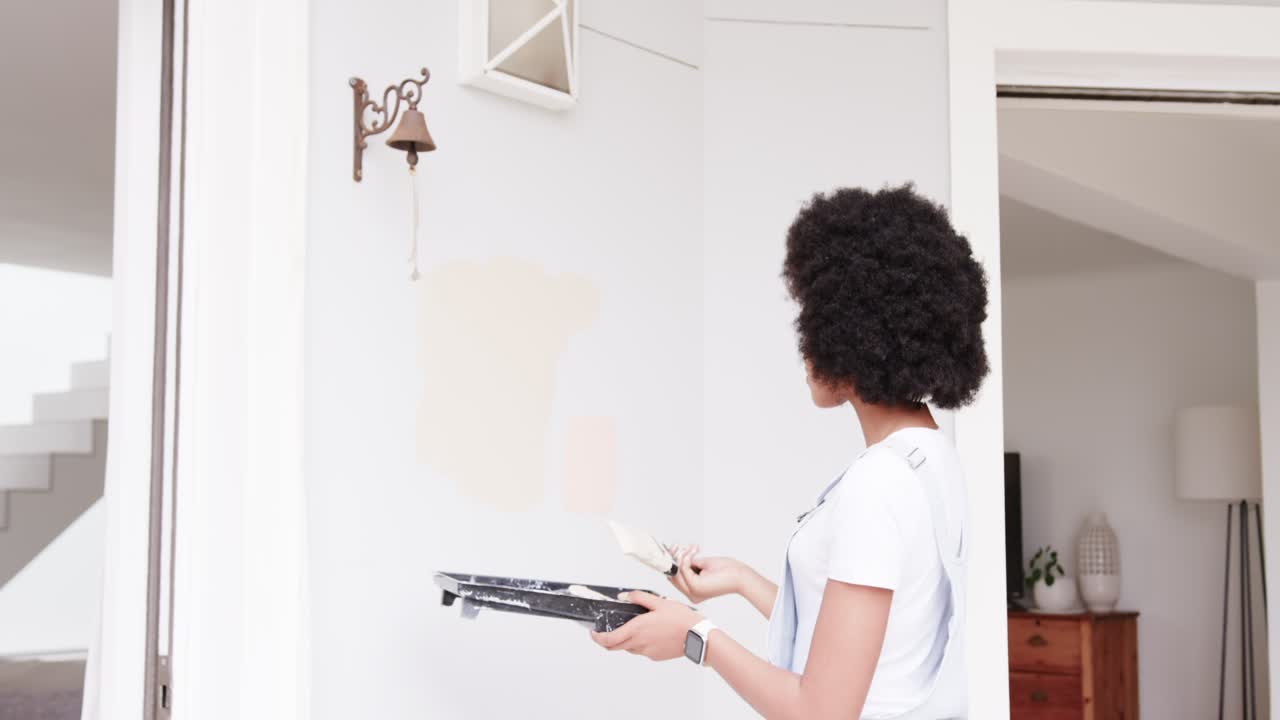 Seeing bell, African woman in apron holding tray, brush, testing samples and picking color at wall