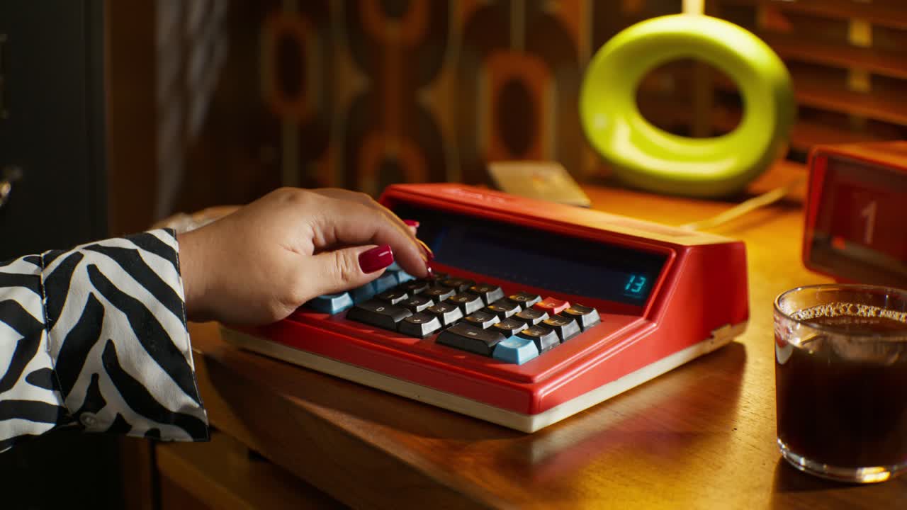 Woman using a vintage calculator at a home office desk