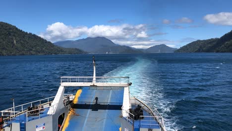 view of the back of a ferry sailing trough mountains, south of chile