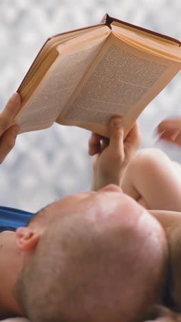 cu shot, dolly cam: young father reads book to blonde little daughter doing homework together on floor in light room at quarantine time closeup