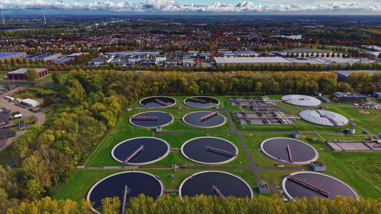 Modern wastewater treatment facility showcases advanced technology and eco friendly practices amidst lush greenery and urban scenery in autumn