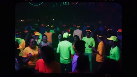 vibrant neon party scene: an energetic crowd dances under colorful lights in a nightclub atmosphere, celebrating with lively music and radiant outfits