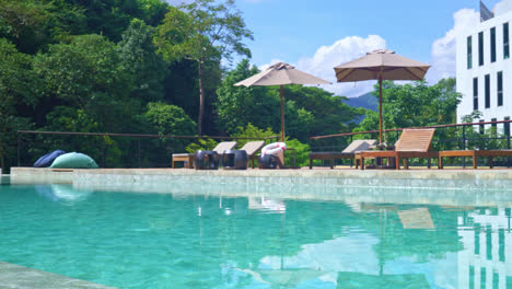 bed pool with umbrella around swimming pool with mountain and blue sky background