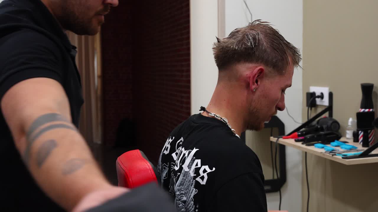 Hairdresser removes black gown from customer after completing haircut