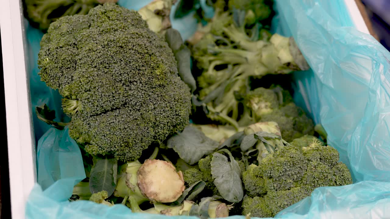 A vibrant market brimming with fresh organic produce showcases a pile of fresh green broccoli nestled in a colorful bag