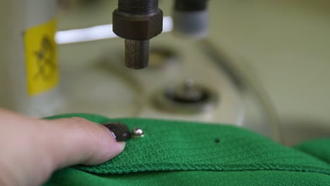 la costurera instala ojos de metal en el uniforme verde de hockey