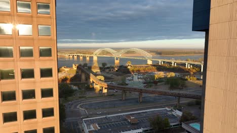 Downtown-Memphis-aerial-reveal-of-Mississippi-river-Interstate-55,-Hernando-de-Soto-bridge-at-golden-hour