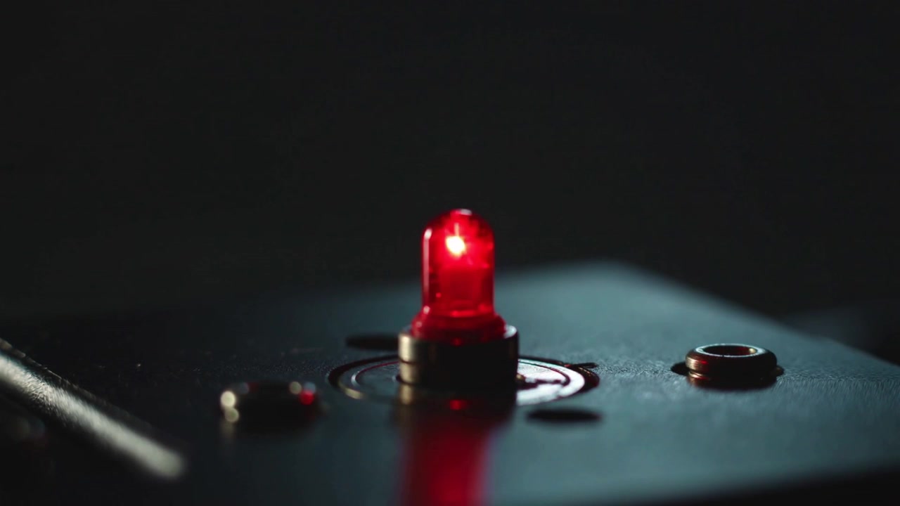 LED indicatore rosso pulsante che segnala lo stato dell'attrezzatura su un pannello di controllo scuro con rivetti a ghiera.