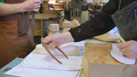 workers in bespoke shoemakers measuring template for last