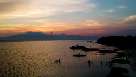 Vista-Aérea-De-La-Puesta-De-Sol-De-Las-Siluetas-De-Los-Barcos-En-La-Playa-De-Paliton-En-Siquijor,-Filipinas