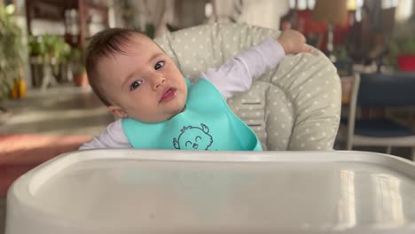 Hungry-baby-ready-for-a-meal,-zoom-out-of-Caucasian-toddler-sitting-in-a-high-chair