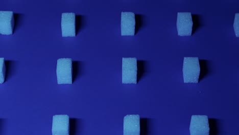 4k slow tilt up view of a unique cubic background with white sugar cubes arranged in rows on a dark blue background, 3d effect