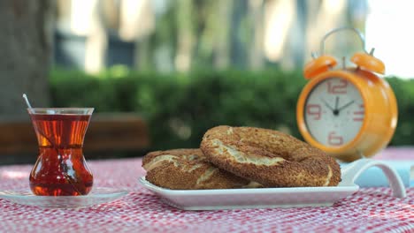 turkish simit served with turkish tea. and an orange clock.